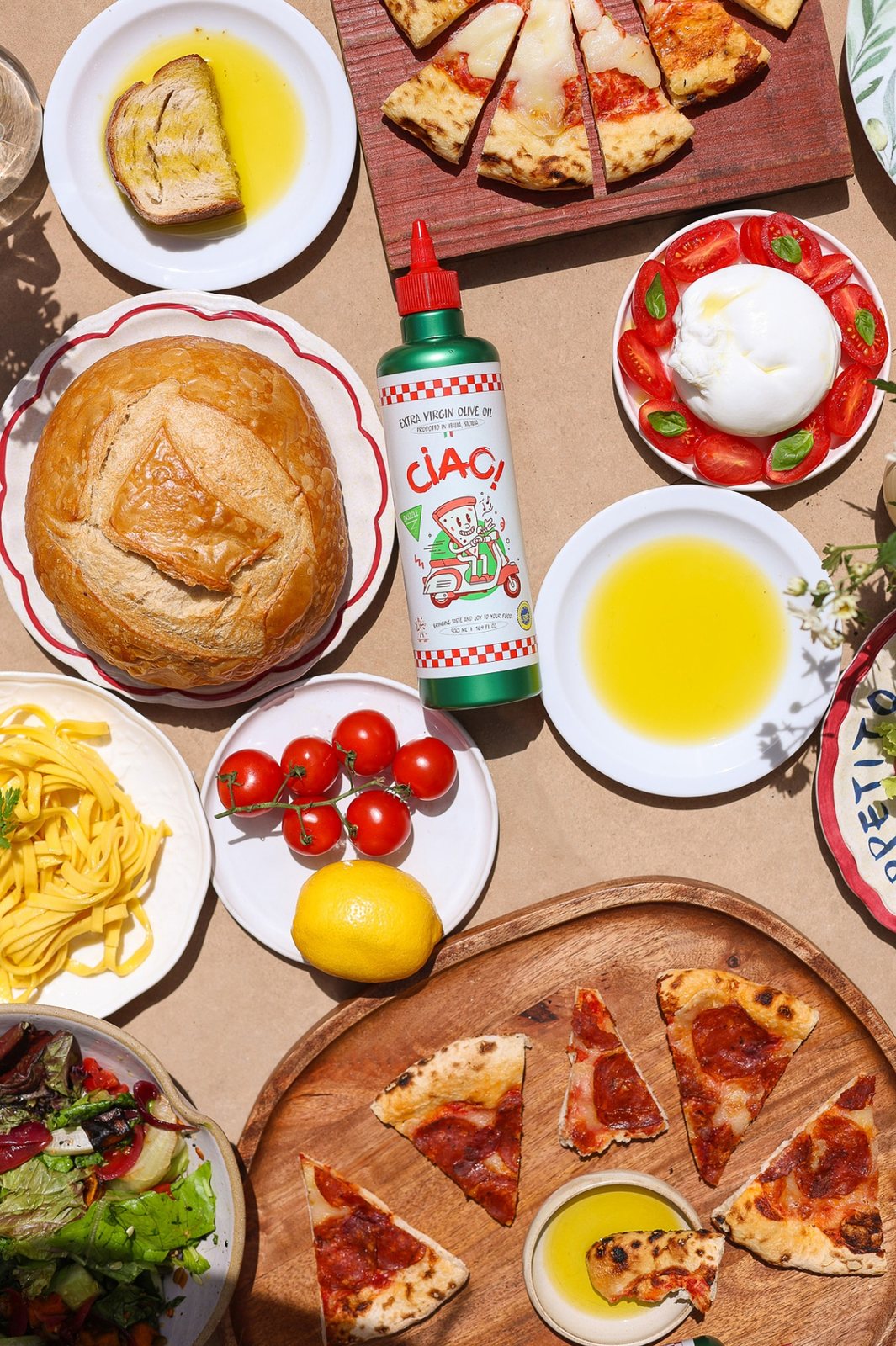 CIAO! Finishing — green squeeze bottle on a Sicilian table with burrata, bread, pasta and pizza